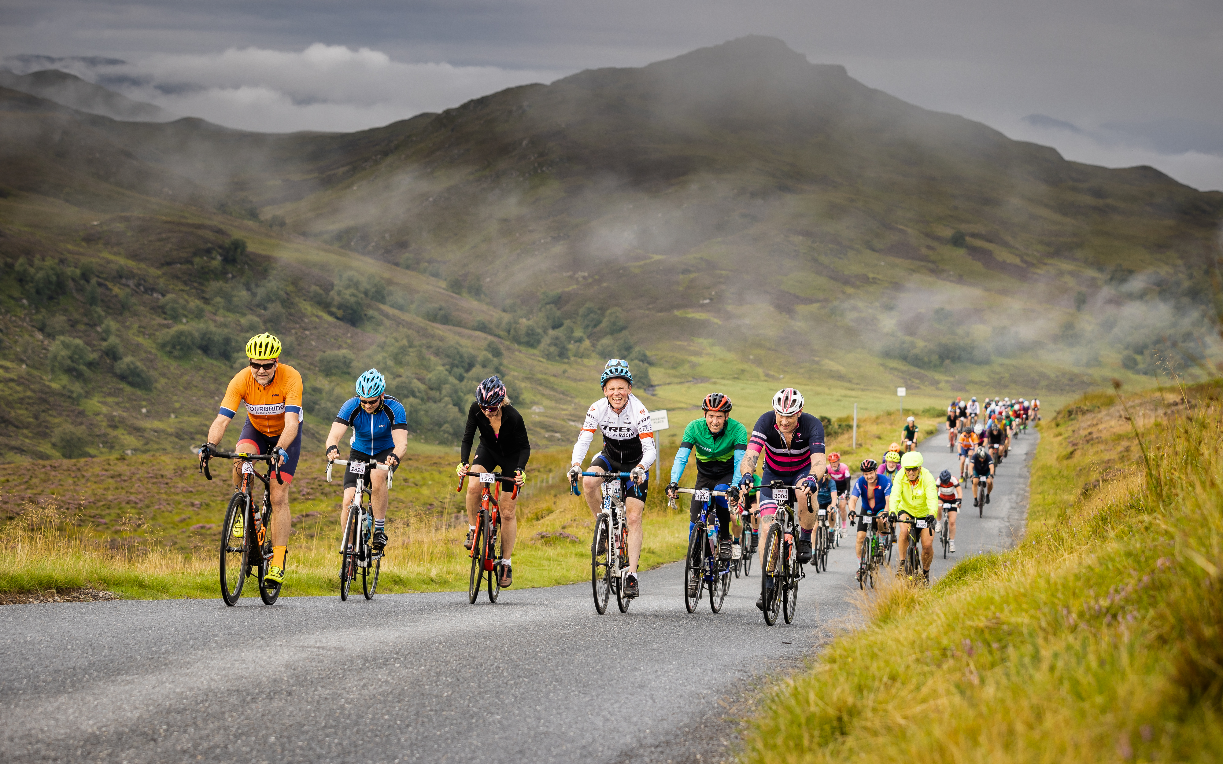 Riders climb an incline with stunning mountains in the background