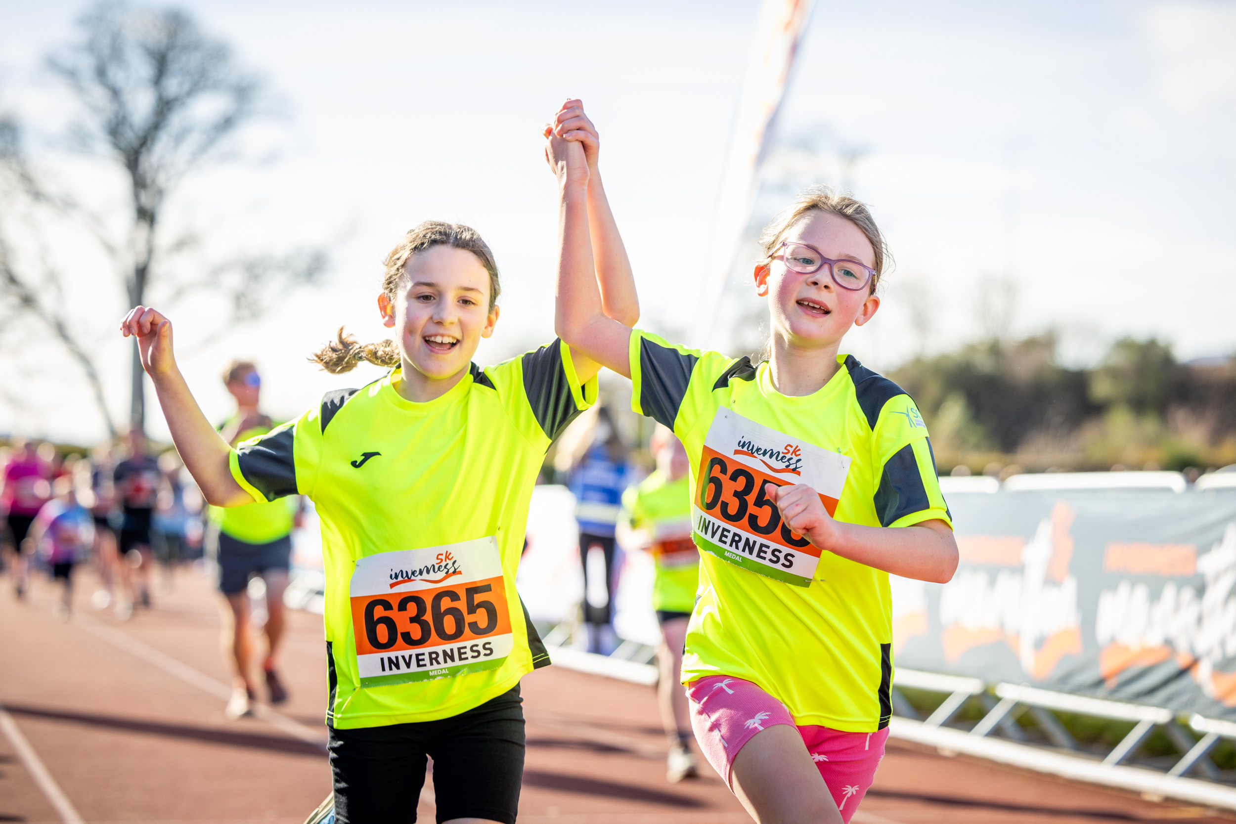 Inverness 5K participants hold hands as they head to the Finish Line
