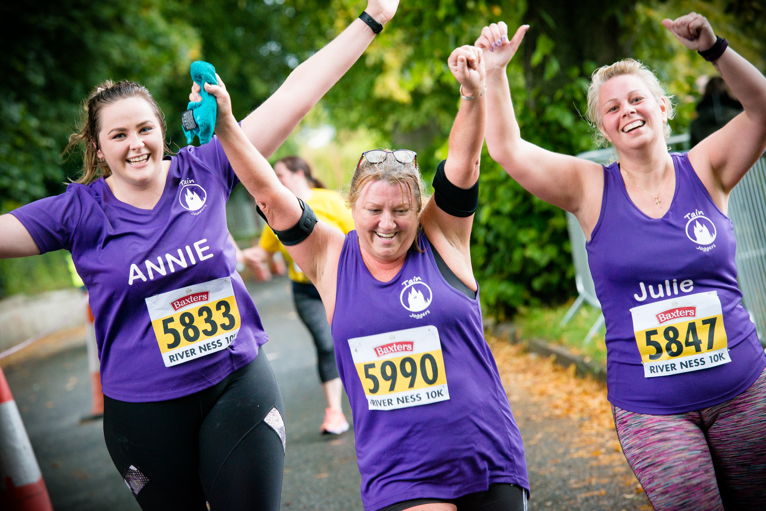 Three Loch Ness participants throw their hands in the air
