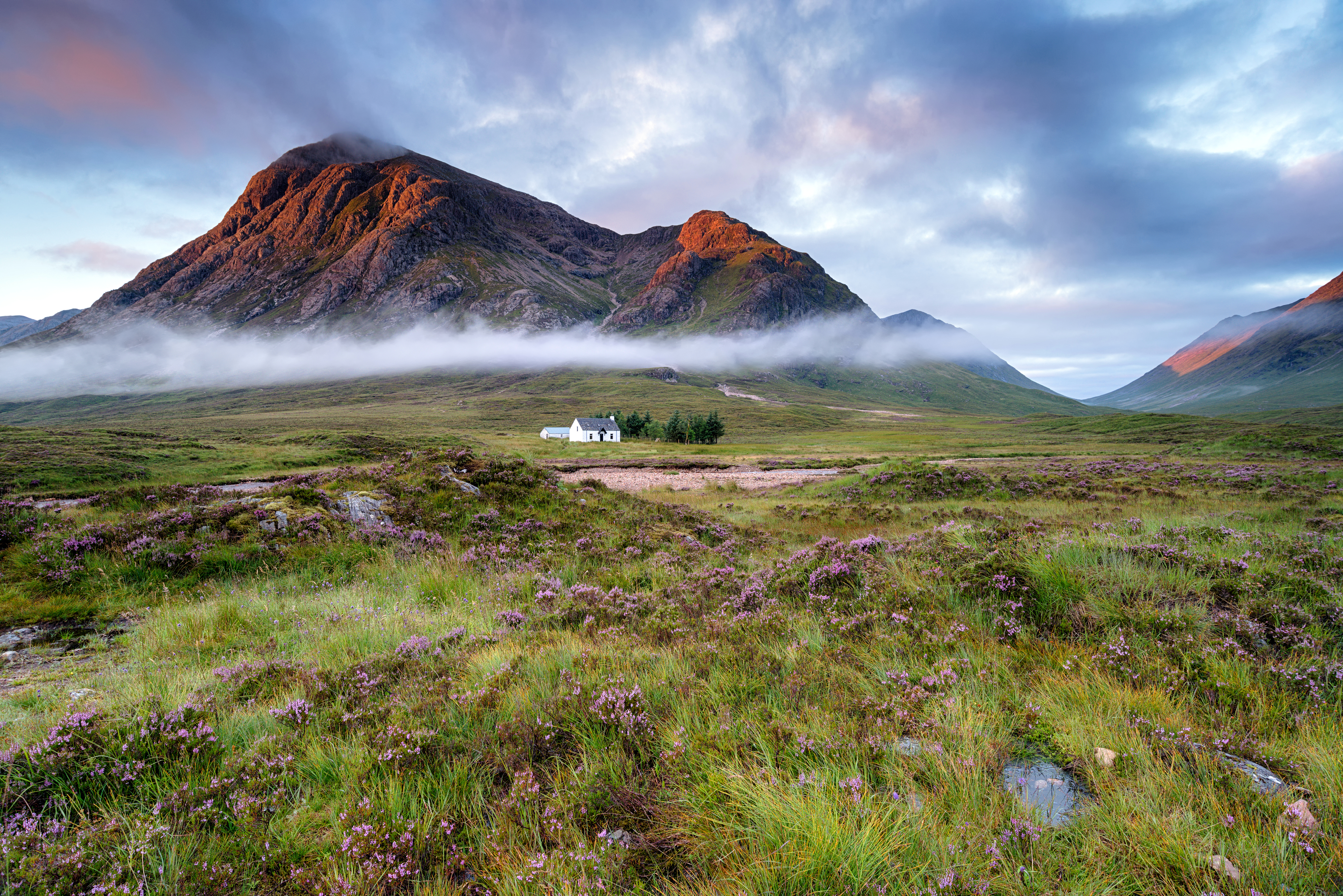 Stunning sunrise over a cottage beneath the mountains at Glencoe in the Scottish Highlands