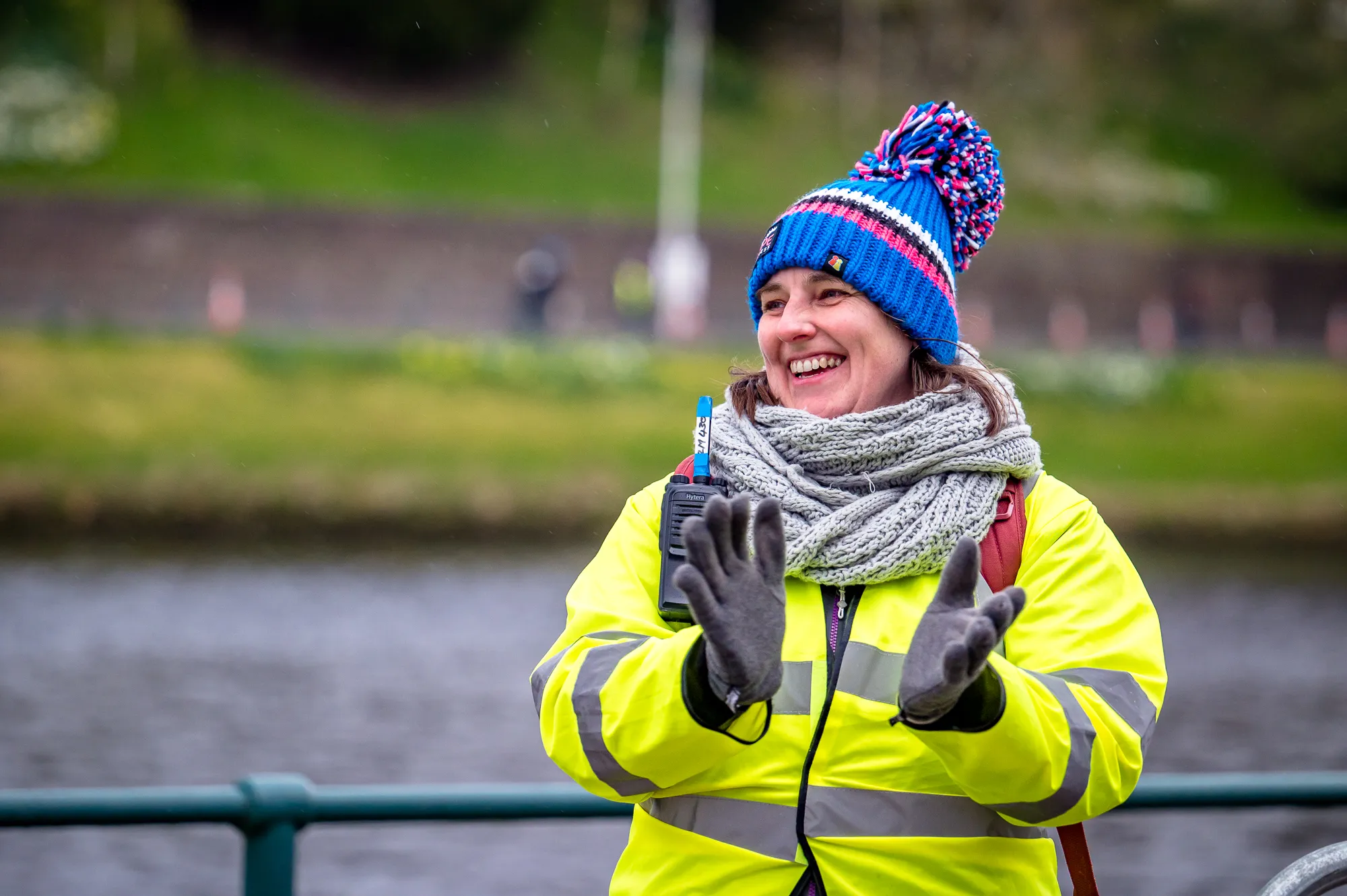 Volunteer in a high viz jacket cheers on participants 
